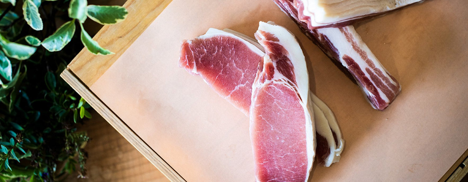 A top down view of Goodwood organic grass-fed West Sussex pork back bacon rashers, displayed on a chopping board at Goodwood Farm Shop.