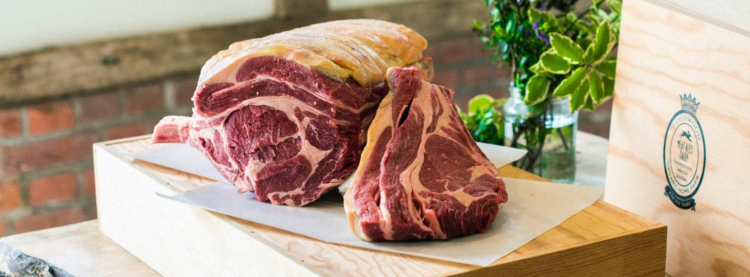A selection of Goodwood organic grass-fed West Sussex meat joints, positioned on a chopping board at the Goodwood Farm Shop.