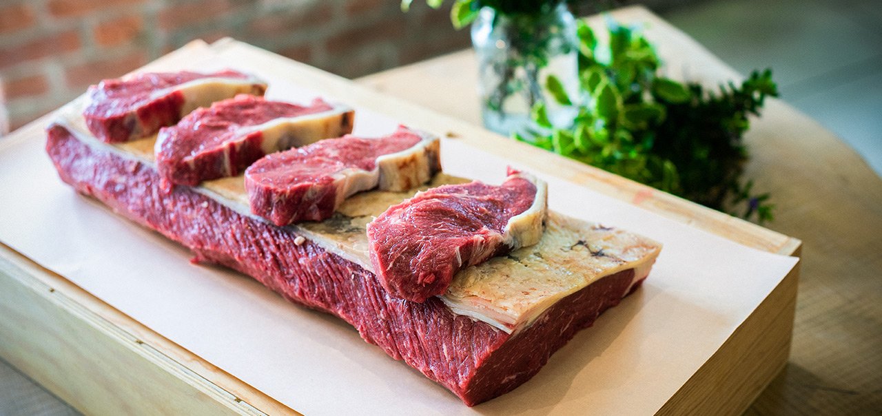 A collection of four Goodwood organic grass-fed West Sussex beef rump steaks sat on a larger cut of organic beef.