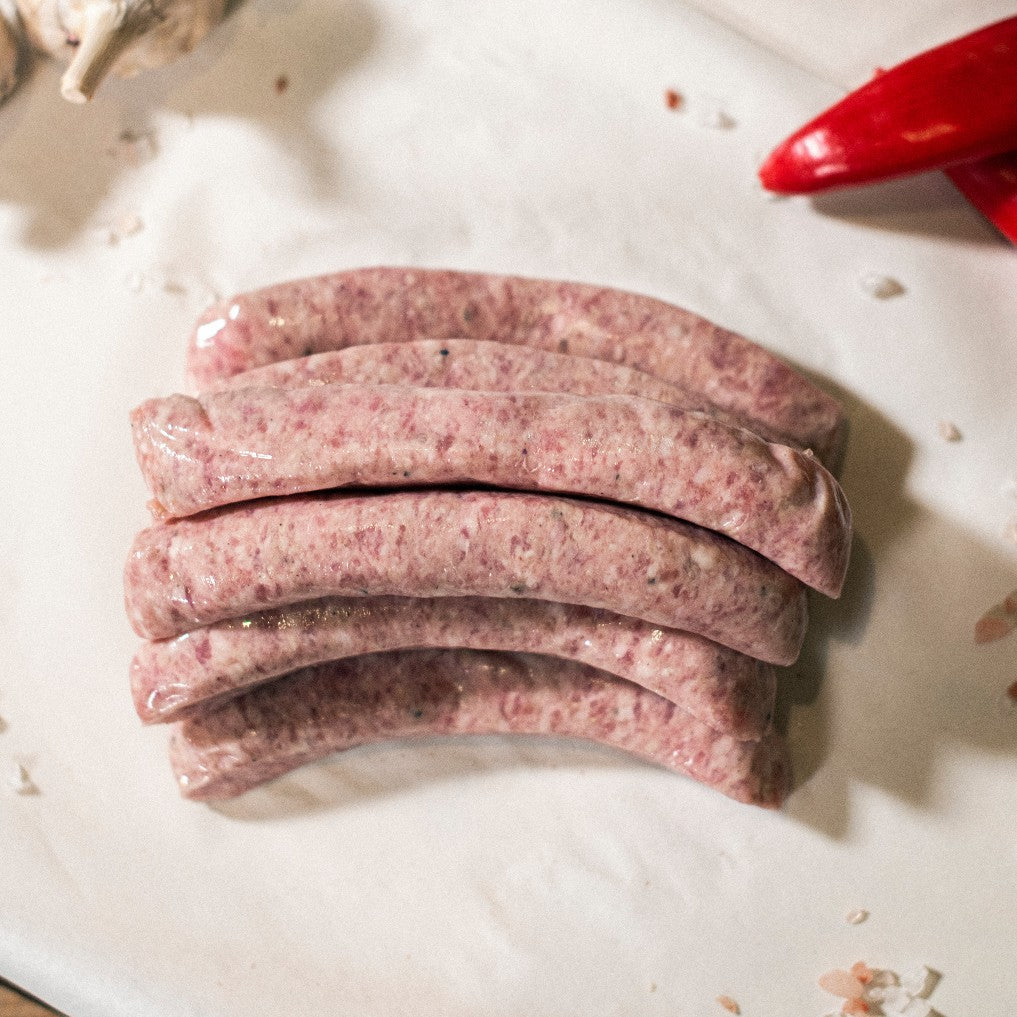 Grass-fed organic chipolata pork sausages shown on a chopping board at Goodwood Farm Shop.