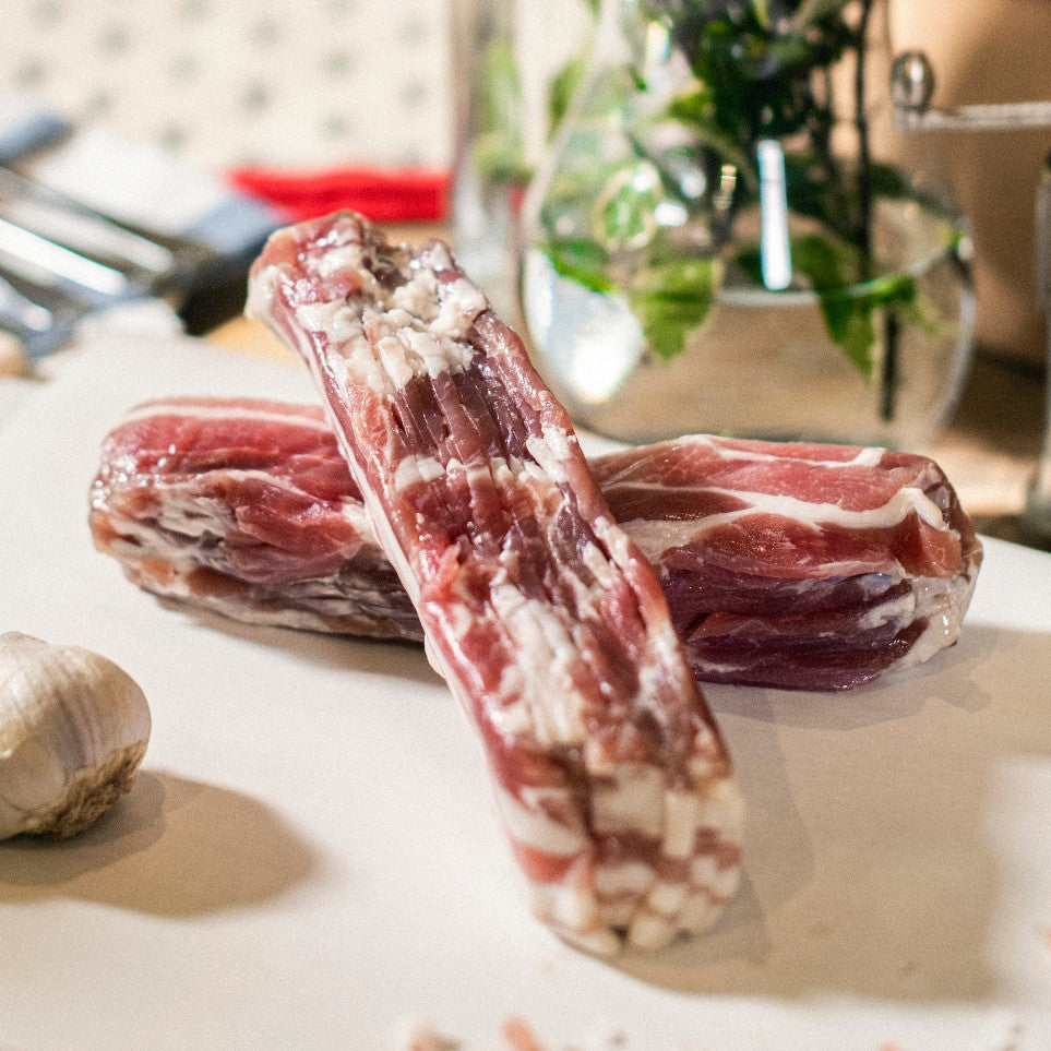 Two sets of Goodwood's organic pork streaky bacon rashers, shown on a chopping board at Goodwood Farm Shop.