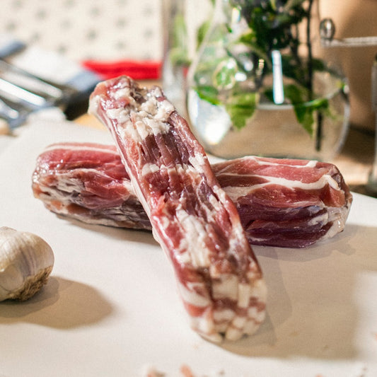 Two sets of Goodwood's organic pork streaky bacon rashers, shown on a chopping board at Goodwood Farm Shop.