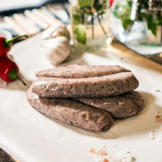 Five Goodwood organic pork and leek sausages on a chopping board at Goodwood Farm Shop.