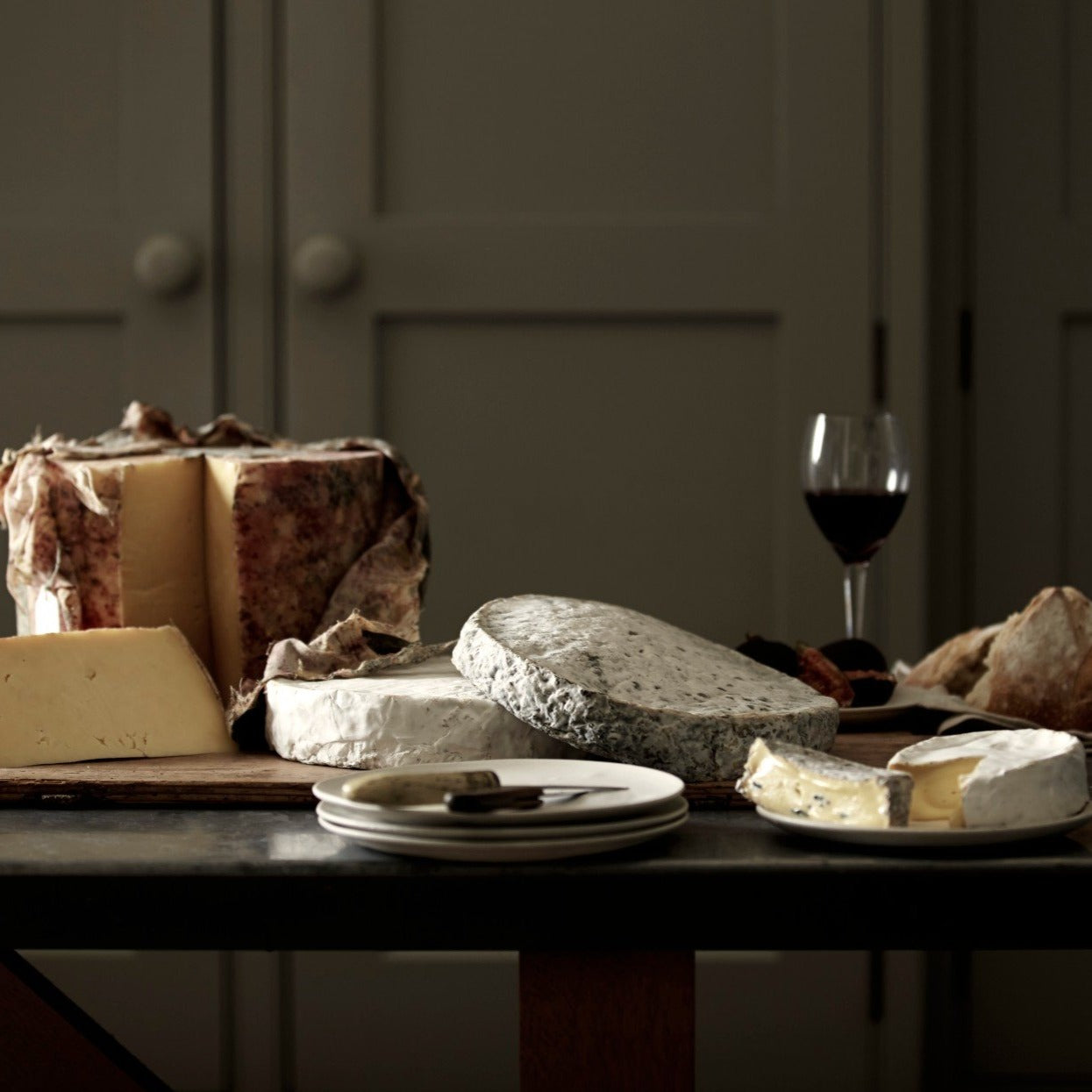 A cheese board selection of handmade Goodwood Farm Shop cheeses, displayed on a table.