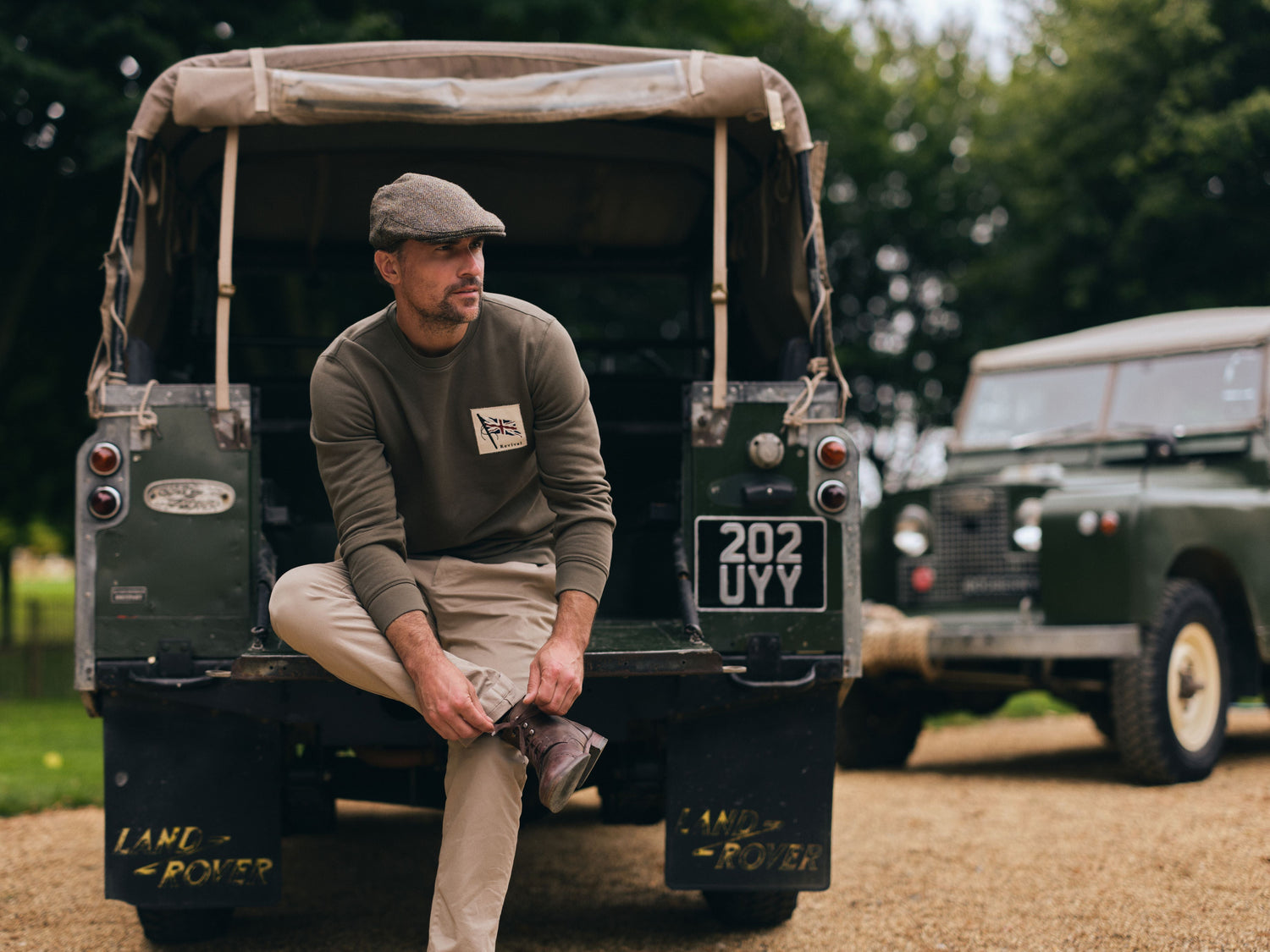 Model wearing Goodwood Revival Flag Sweatshirt sat in the back of a Land Rover