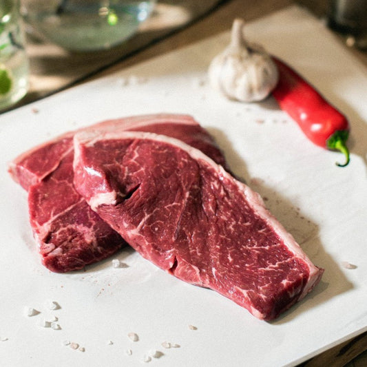A top down view of Goodwood's organic grass-fed Sussex beef rump steak, displayed on a chopping board at Goodwood Farm Shop.
