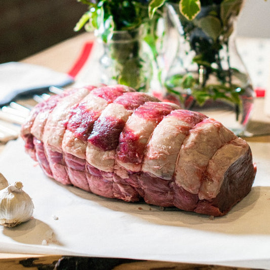 Organic grass-fed Sussex beef topside roasting joint displayed on a chopping board at the Goodwood Farm Shop.