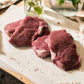 Close up of four organic grass-fed lamb leg steaks on a chopping board at the Goodwood Farm Shop.