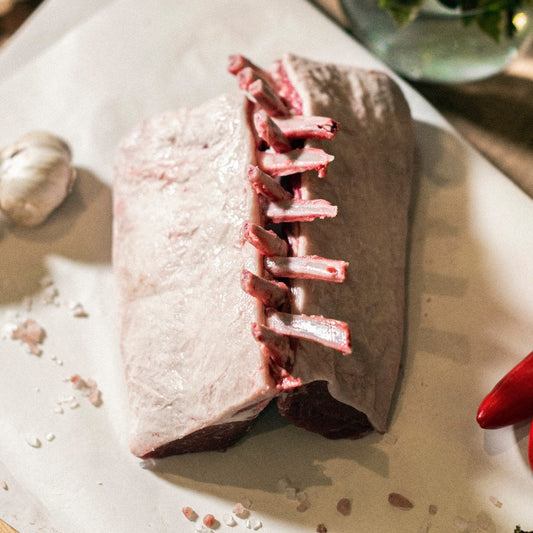 A pair of organic grass-fed racks or lamb, displayed in a guard of honour on a chopping board at the Goodwood Farm Shop.