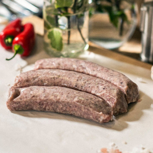 Three Goodwood organic Cumberland pork sausages on a chopping board at Goodwood Farm Shop.