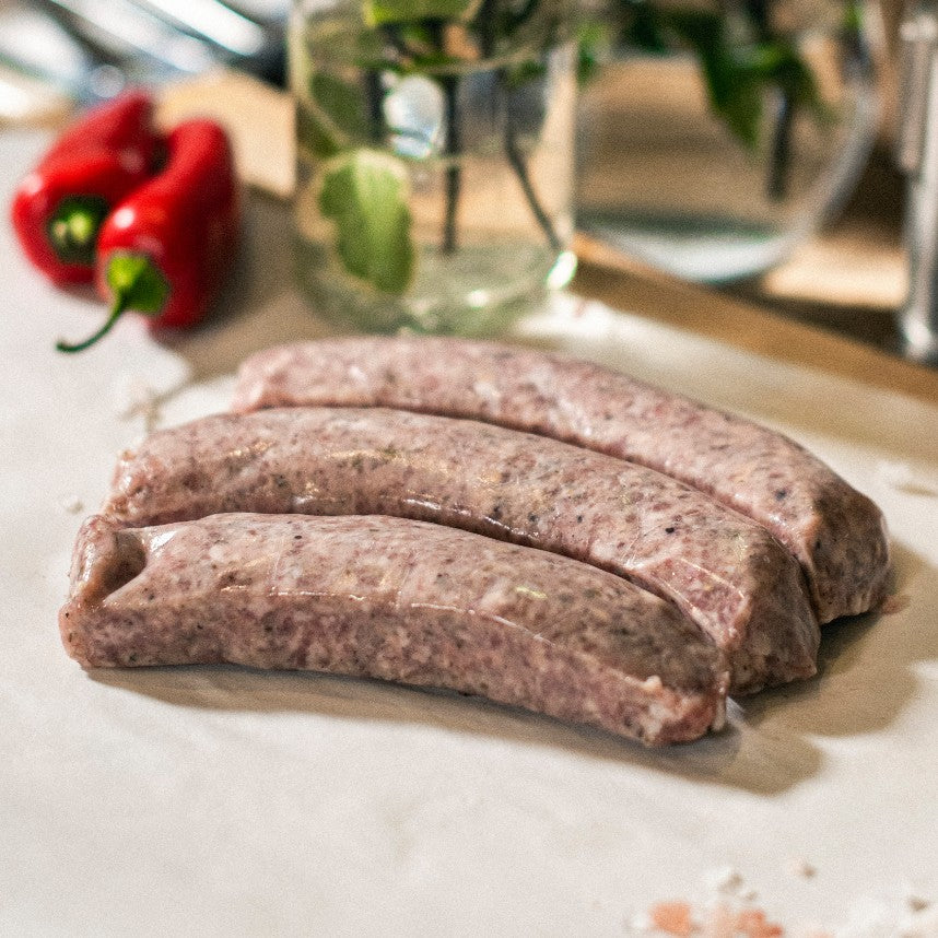 Three Goodwood organic Cumberland pork sausages on a chopping board at Goodwood Farm Shop.