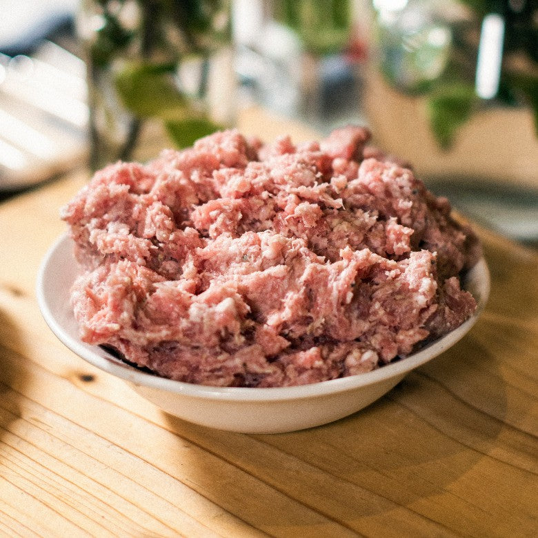 A bowl of Goodwood's organic grass-fed pork sausage meat, suitable to be turned into pork stuffing, displayed on a chopping board at Goodwood Farm Shop.