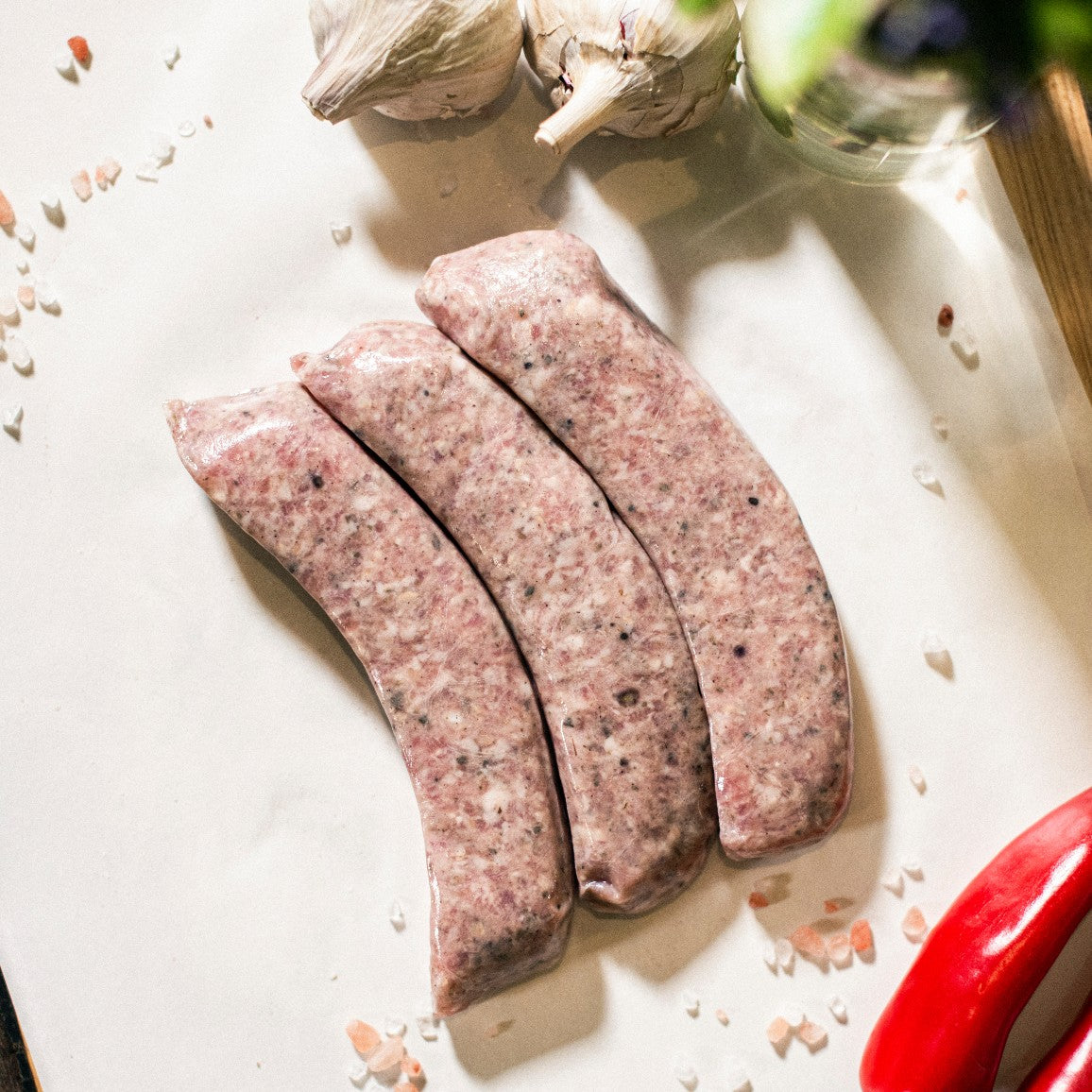 Three Goodwood organic pork sausages on a chopping board at Goodwood Farm Shop.