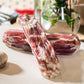 Two sets of Goodwood's organic pork streaky bacon rashers, shown on a chopping board at Goodwood Farm Shop.