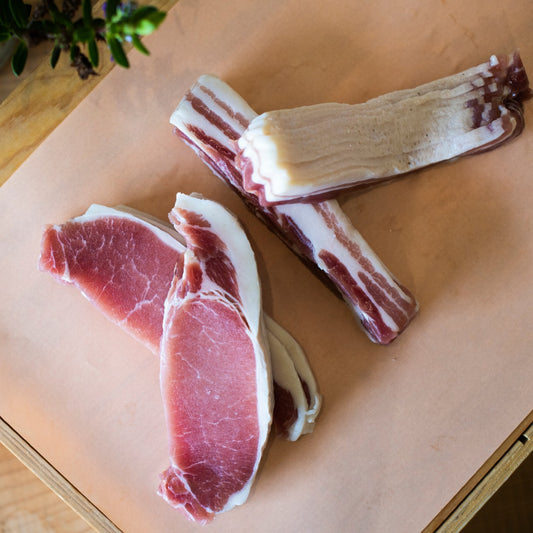 Four sets of Goodwood's organic back bacon rashers, displayed on a chopping board at Goodwood Farm Shop.
